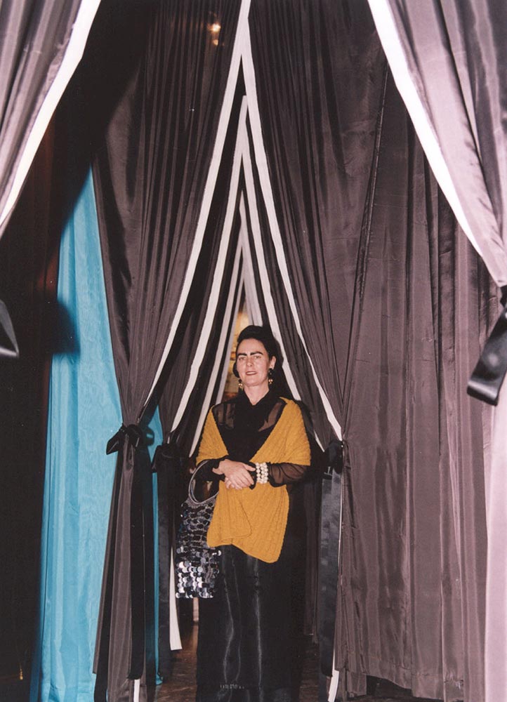 Jacqueline Fraser standing between two rows of draped curtains.