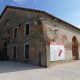 Outside view of Tesa dell'Isolotto. An old, long brick building, with craved archways cut into the right side of the building.