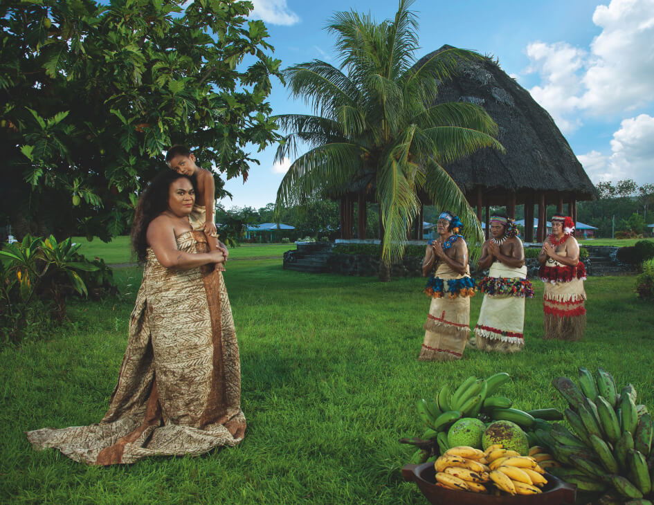 Three figures in Sāmoan cultural dress face a Fa‘afafine (Sāmoa’s third gender) wearing a siapo and carrying a young boy.