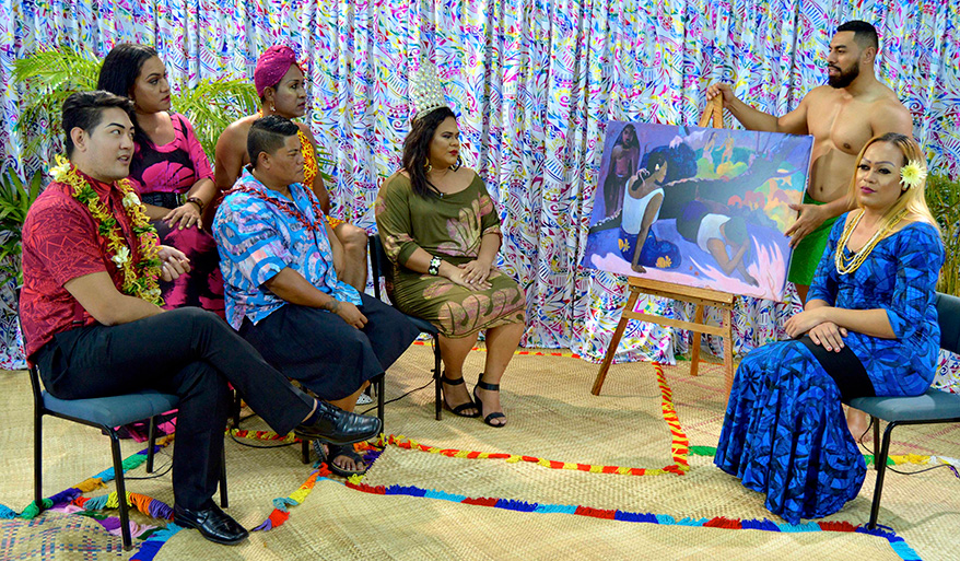 A room of people sitting, looking at a painting