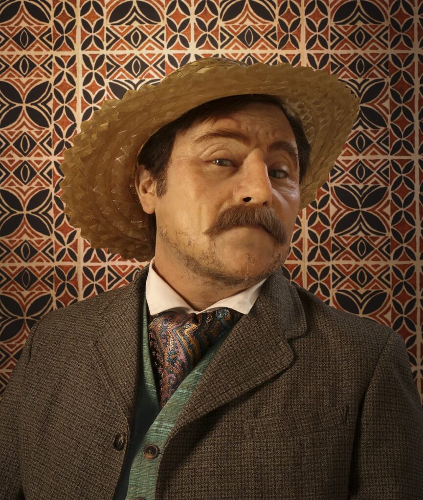 man in a hat, tilting his head to look at the camera